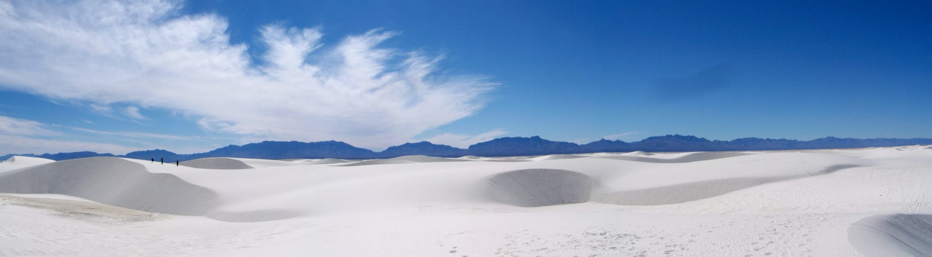 Hikers crossing the white gypsum dune field along the Alkali Flat Trail