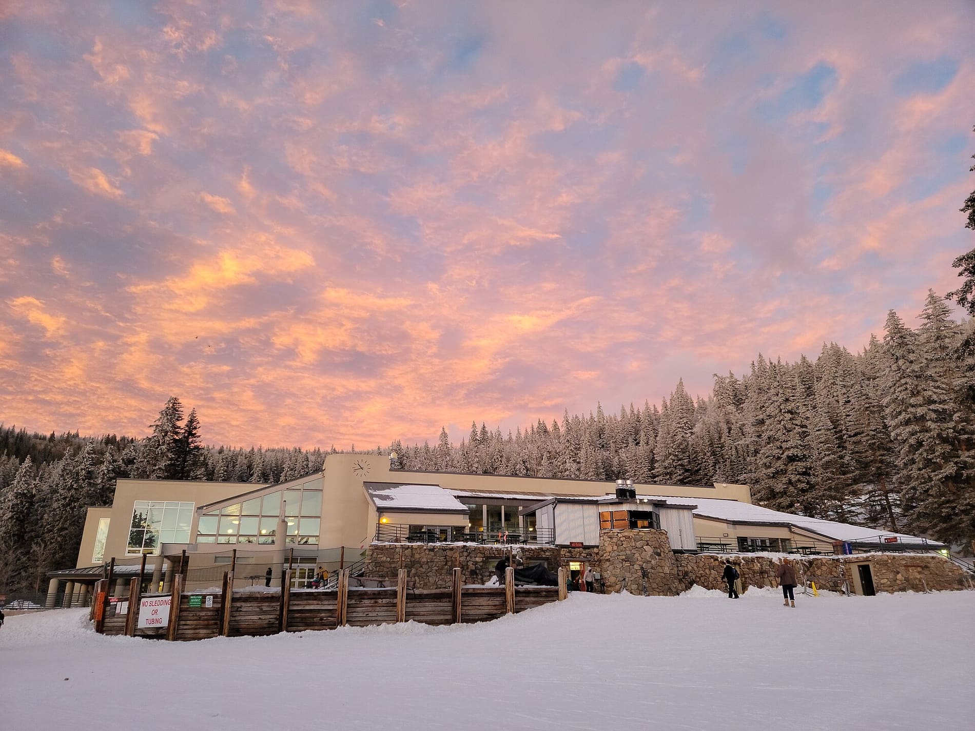 Ski Santa Fe base lodge at dusk with snow-dusted evergreens behind it